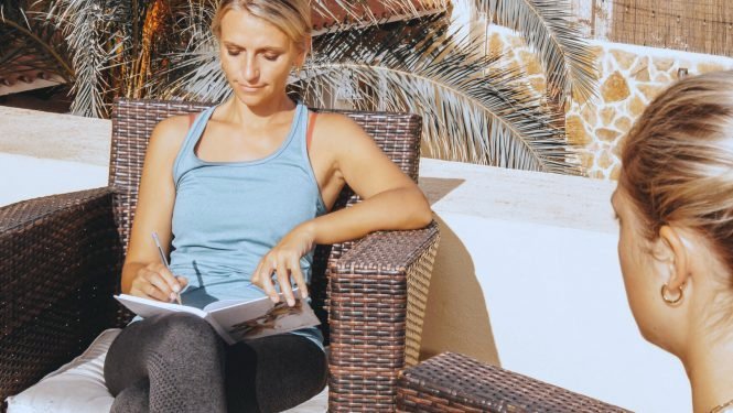 Nina Wassinger sitzt mit Notizbuch im Gespräch mit einer Klientin