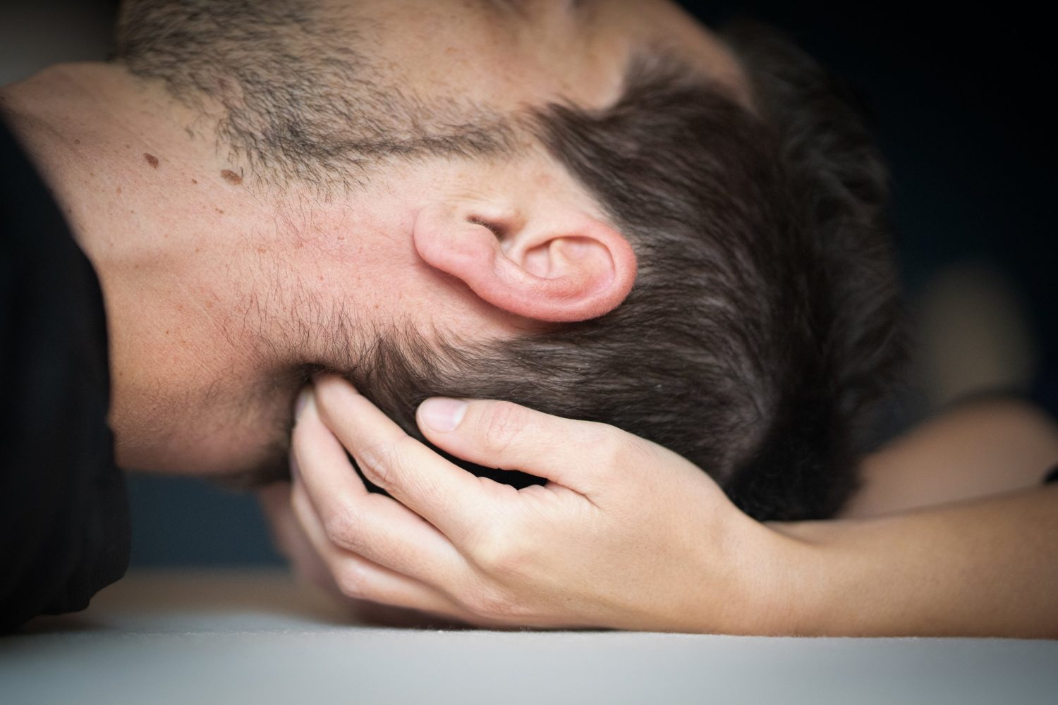 Eine Hand hält bei der osteopathischen Behandlung behutsam den Hinterkopf eines liegenden Patienten